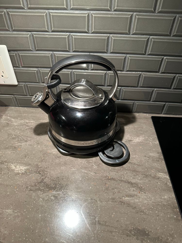 A black stovetop kettle sitting on a kitchen counter. 