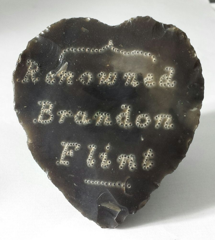 A heart shaped flint facing stone, with the words 'renowned Brandon flint' pecked in the surface, c.1930