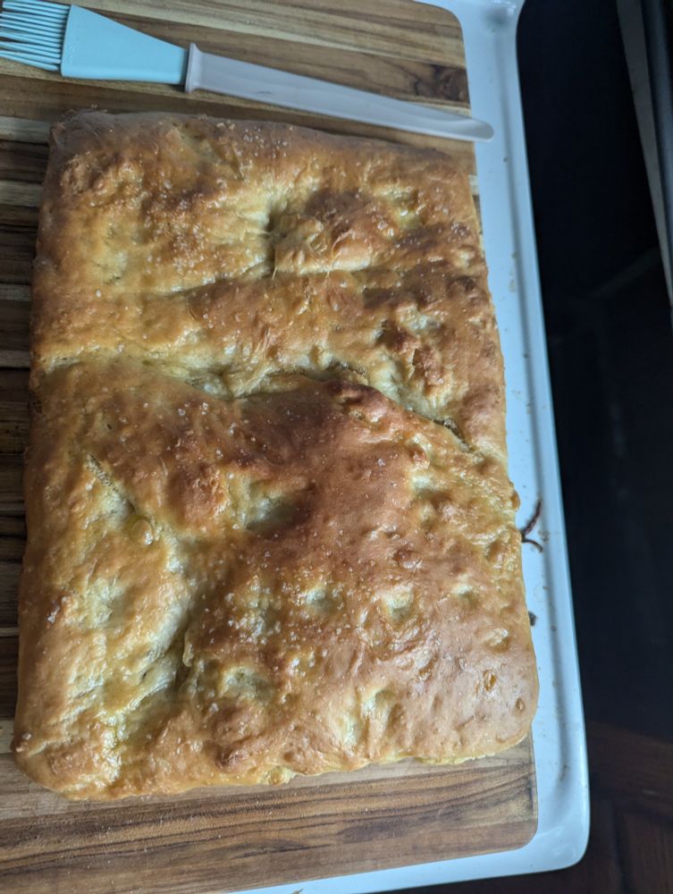 Rectangular loaf of focaccia on a wooden cutting board. 