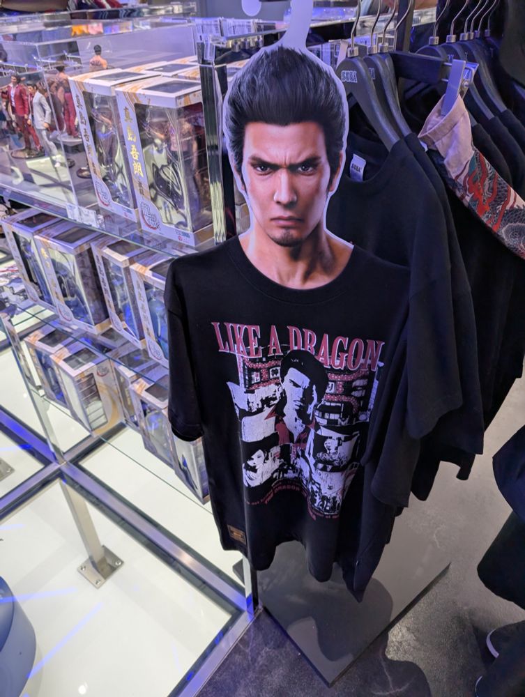A coat hanger from the Shibuya sega store. The coat hanger itself is just Kazuma Kiryu's face and shoulders and it's wearing a Like a Dragon shirt. He looks very, very serious.
