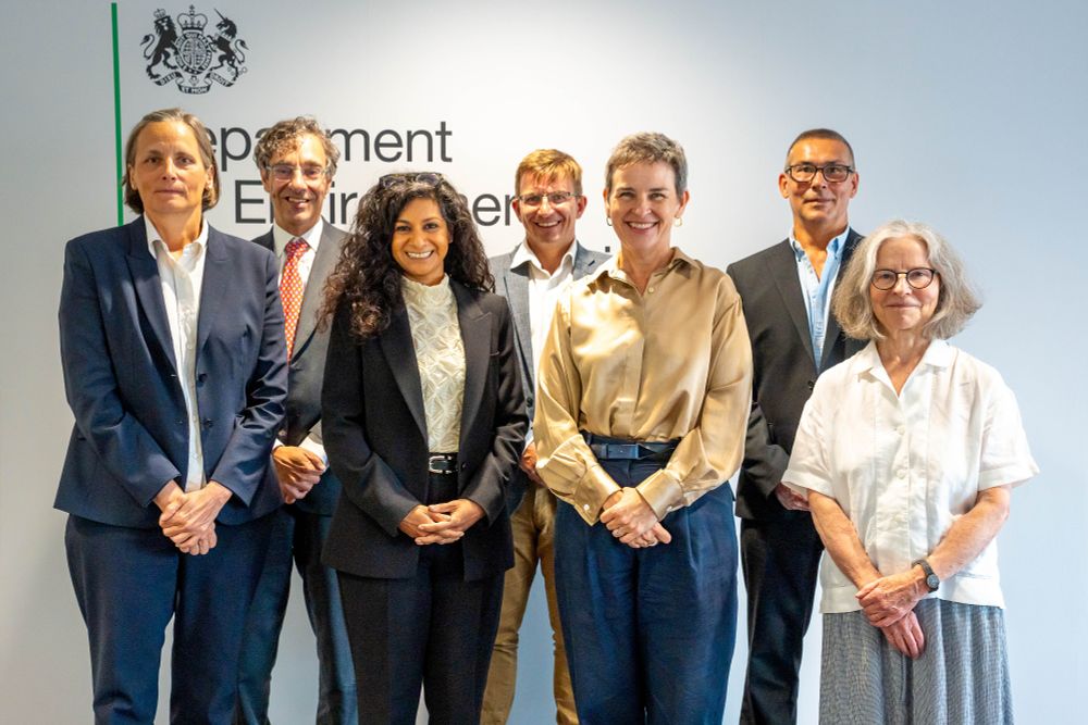 Image of seven people standing in front of a large Defra logo