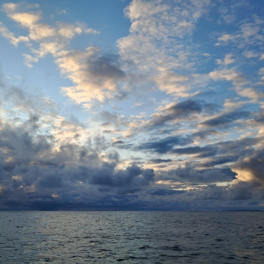 A colour image of calm seas, with clouds and blue sky above copyright Bryony Baker