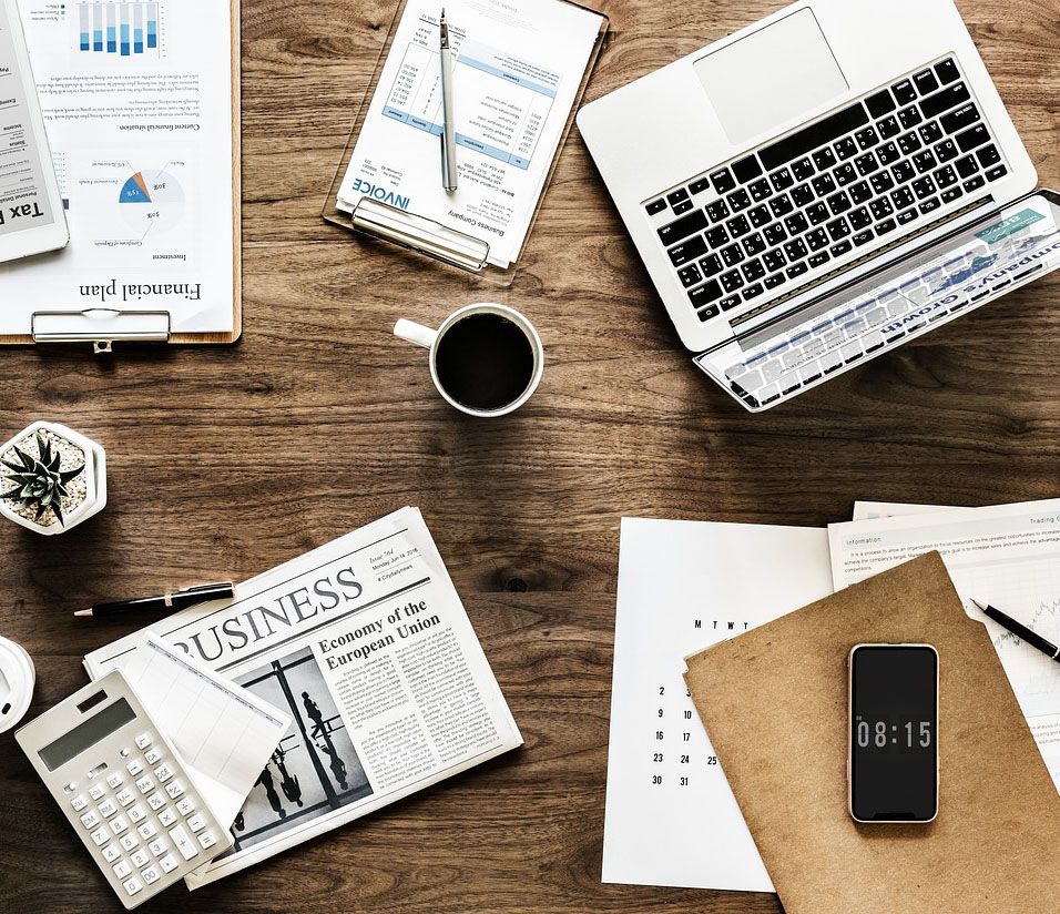 A colour photograph of a desk, with various finance-related papers and a laptop.