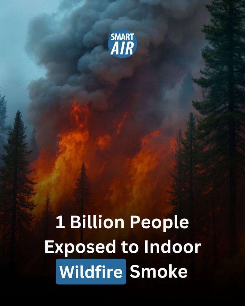 A forest wildfire rages with tall orange flames and thick black smoke rising into the sky. The scene is overlaid with the logo "SMART AIR" near the top, and bold white text at the bottom reads: “1 Billion People Exposed to Indoor Wildfire Smoke,” with the word “Wildfire” highlighted in a blue box.