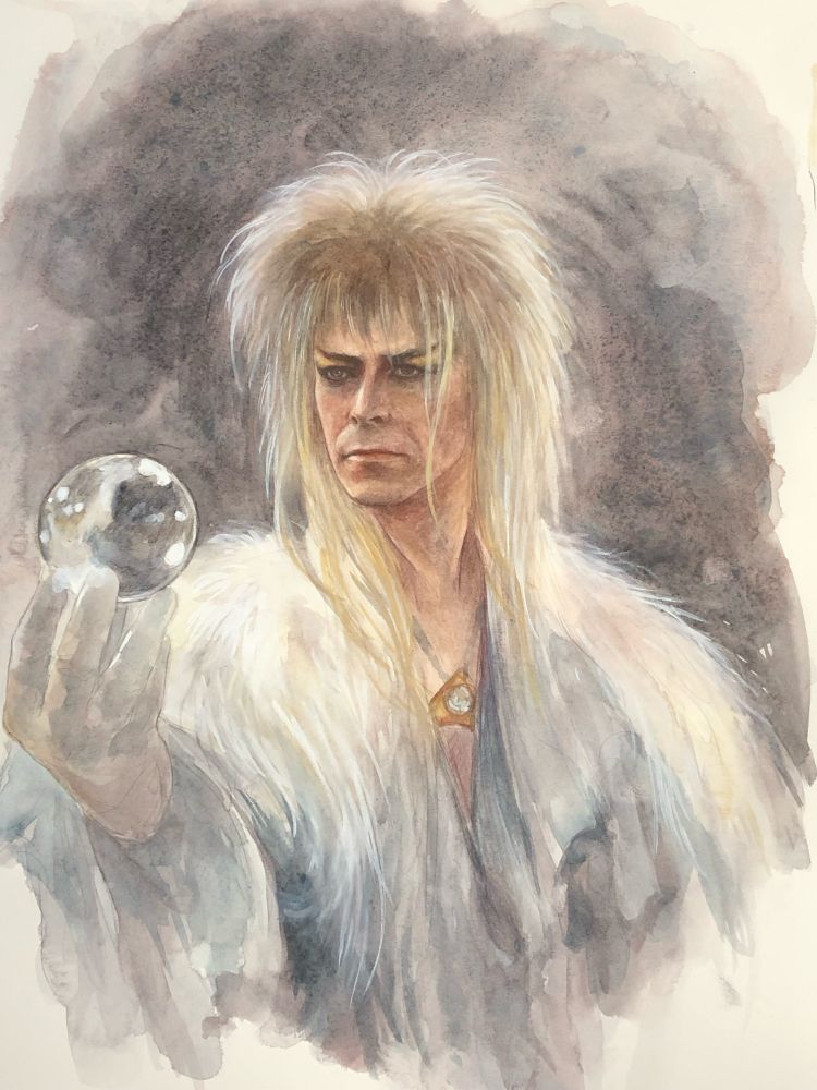 David Bowie as Jareth the Goblin King from the movie Labyrinth wearing a white cloak and holding a crystal ball in his hand 