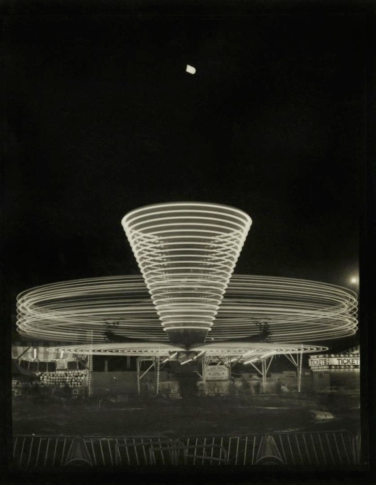 Parallel strips of light form a conical shape and layered rings as the ride spins at night 