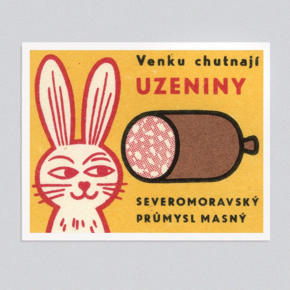 A graphic illustrated matchbox label which has a sausage on the right, cut open to show its texture. On the left is a sly eyed rabbit eyeing up said sausage 