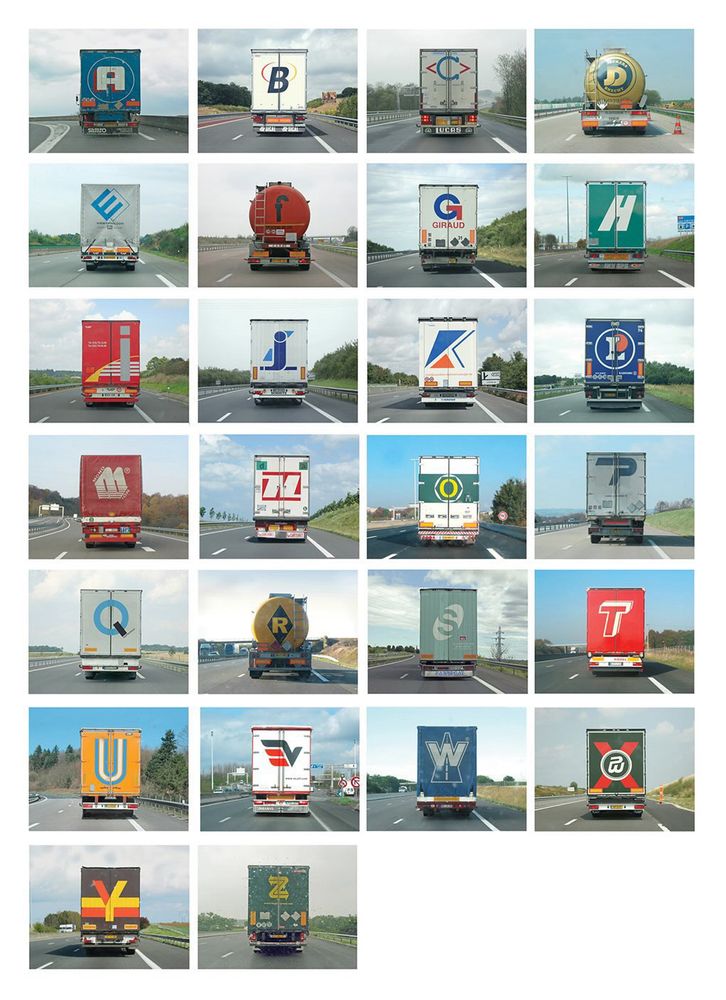 A grid of photos. The back of 26 trucks/Lorries and each one has a logo corresponding to a letter on the alphabet. Mixed colours and typographic styles 