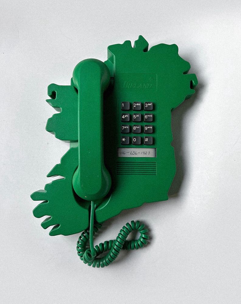 A wall phone that is green and in the shape of Ireland. 