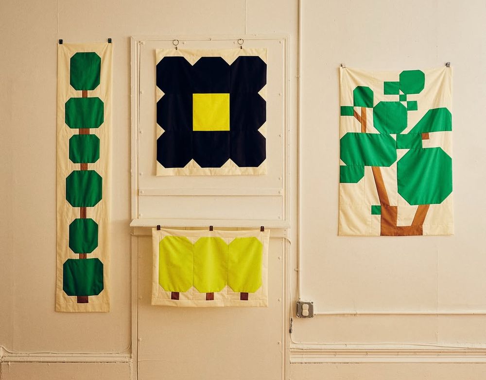 A cute selection of tree like graphics made from textile panels, all hanging on a wall 