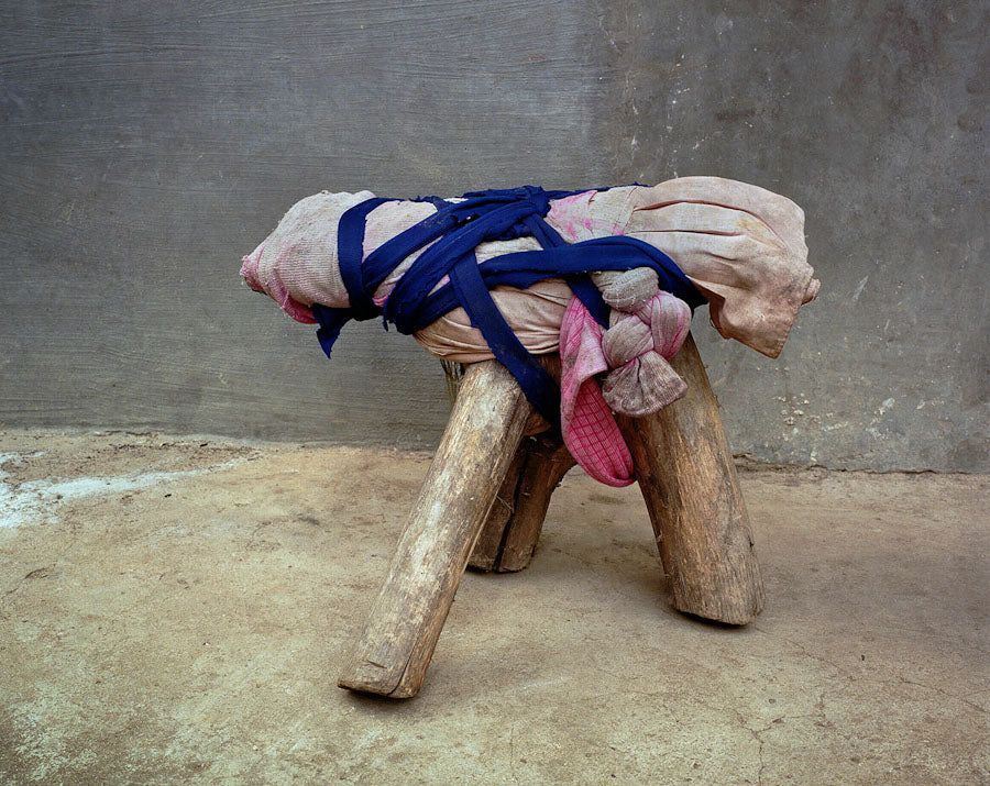 a stool made of logs and bundles of fabric all tied together