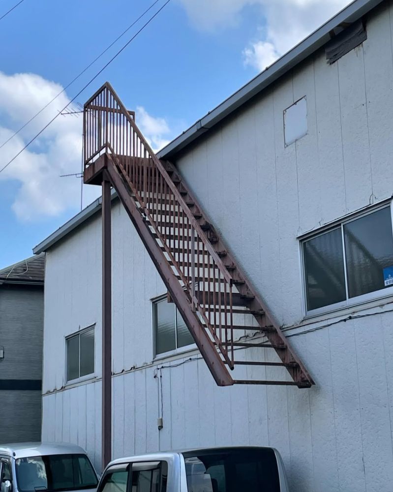 an iron staircase runs down the side of a building but stops at the first floor