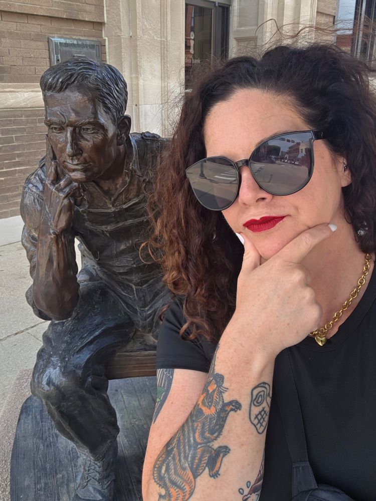 Me by a statue of a man in a thoughtful pose (both are)