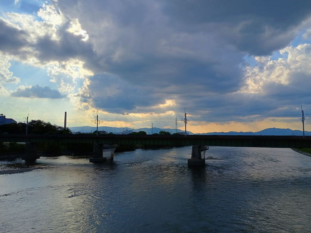 Alt: pictured is a bridge above a river at sunset 