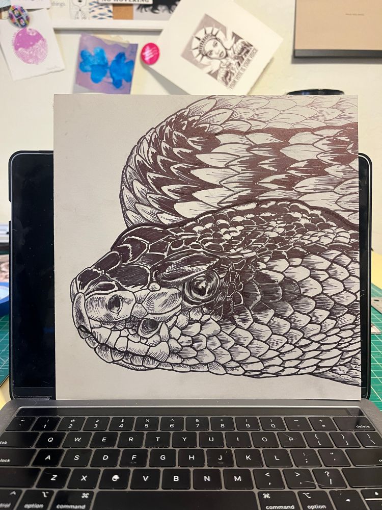 Battleship gray linoleum block with a rattlesnake drawn on it in sharpie. 