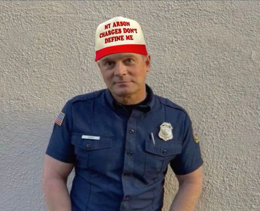 bobby with hands in his pockets with a hat that says "my arson charges dont define me"