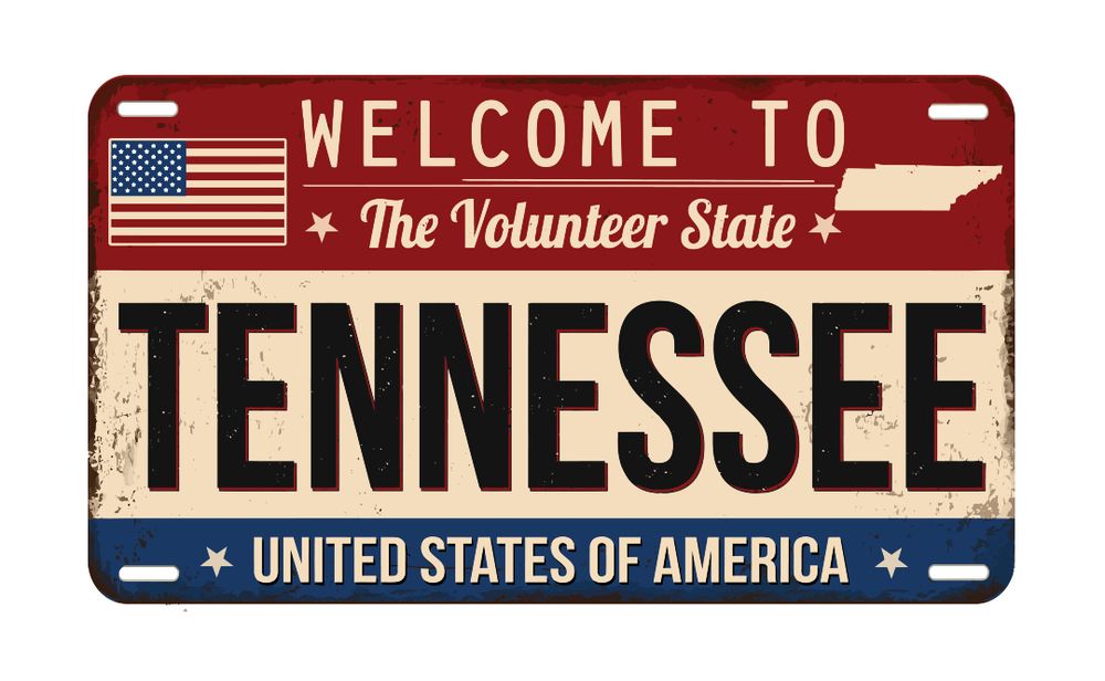 Vintage-style Tennessee license plate with "Welcome to The Volunteer State" and "United States of America" text, featuring a small American flag.