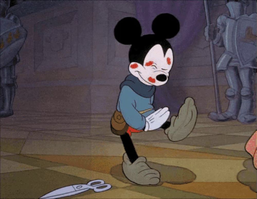 a cartoon of mickey mouse standing next to a pair of scissors on the floor