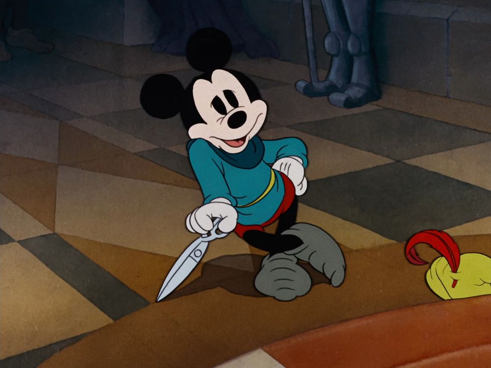 Mickey leaning on his huge sewing scissors in his cartoon 'Brave Little Tailor' (1938).