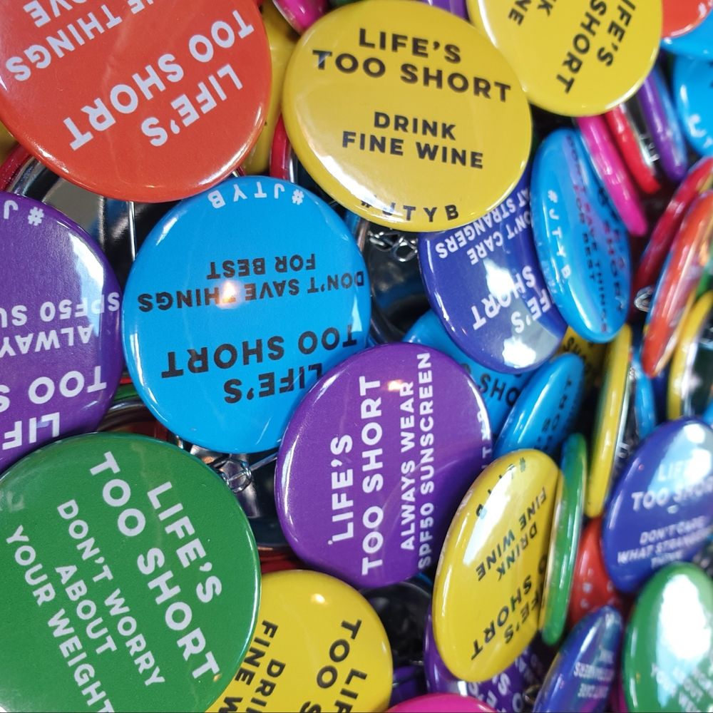 Colourful funeral badges with eight bespoke mottos for life on them - such as LIFE'S TOO SHORT, ORDER THE LOBSTER - for one of our 2024 clients, who we supported to plan her funeral before she died. 