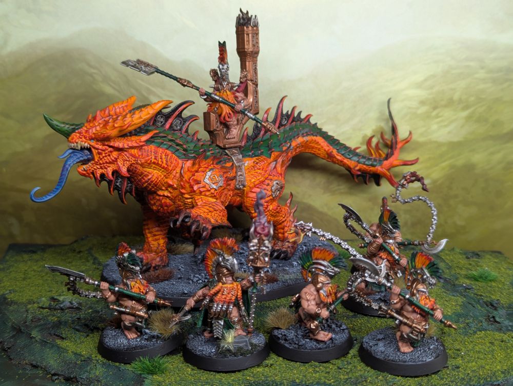 A magmadroth and some hearth guard berserker models from Games Workshop. The magmadroth is painted bright orange.