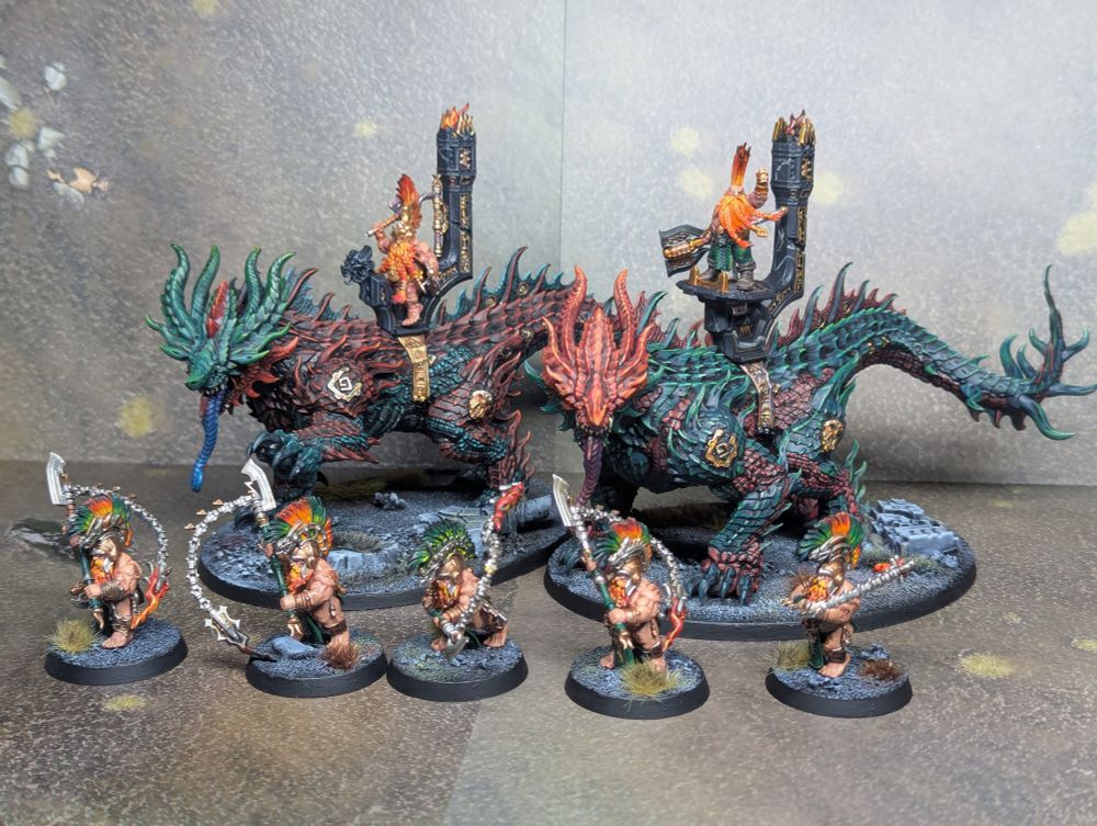 Two magmadroths and some hearth guard berserker models from Games Workshop. The magmadroths are painted in a red and green colour scheme.