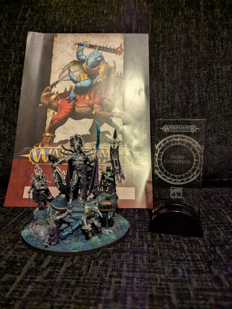 A Warhammer store champion trophy and a certificate, posed next to an Ossiarch Bonereapers model.