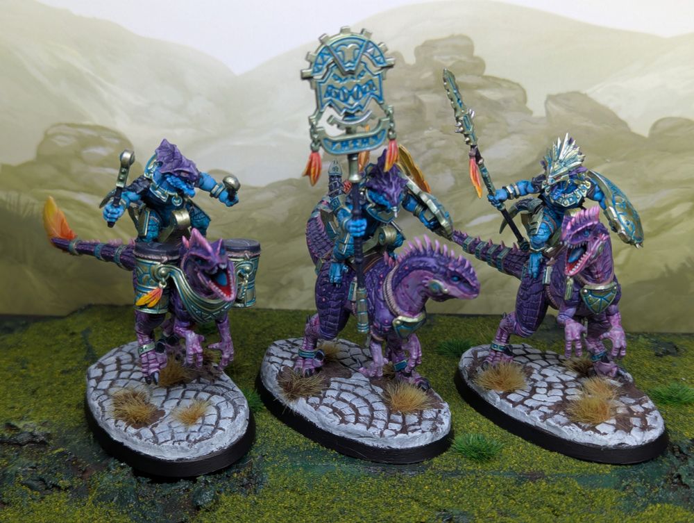 Three Games Workshop aggradon lancer models. The riders are painted with blue skin and the mounts with purple skin. The bases are painted as white stone.