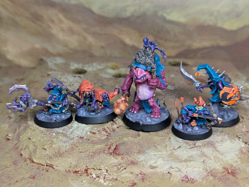The Borgit's Beastgrabberz warband from Games Workshop. There are four goblins and a troll, painted with purple skin, blue clothes and orange as a spot colour.