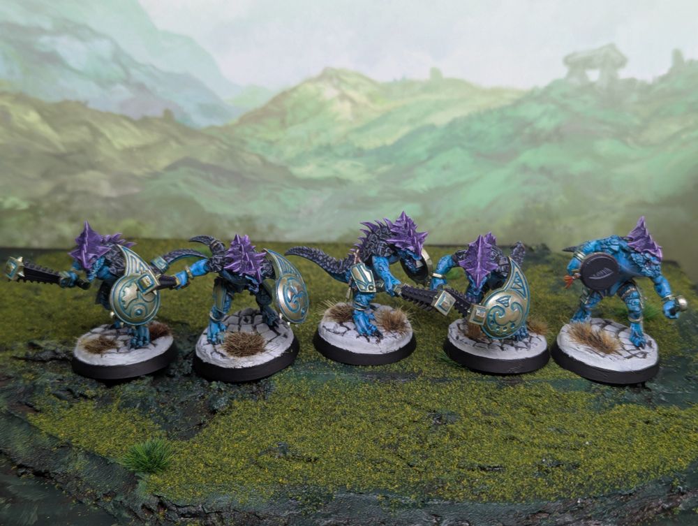 Five Games Workshop saurus warriors. They are painted with purple crests, blue skin and pale gold metallics.