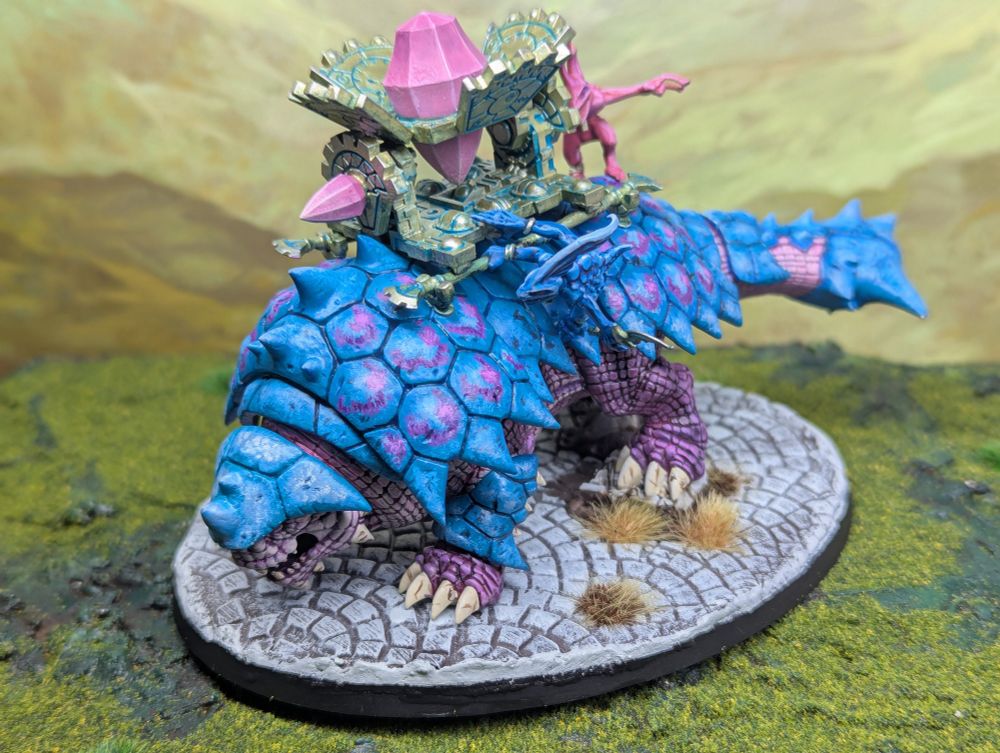 A bastiladon model from Games Workshop (looks like an Ankylosaurus dinosaur), painted in a pink and blue colour scheme.