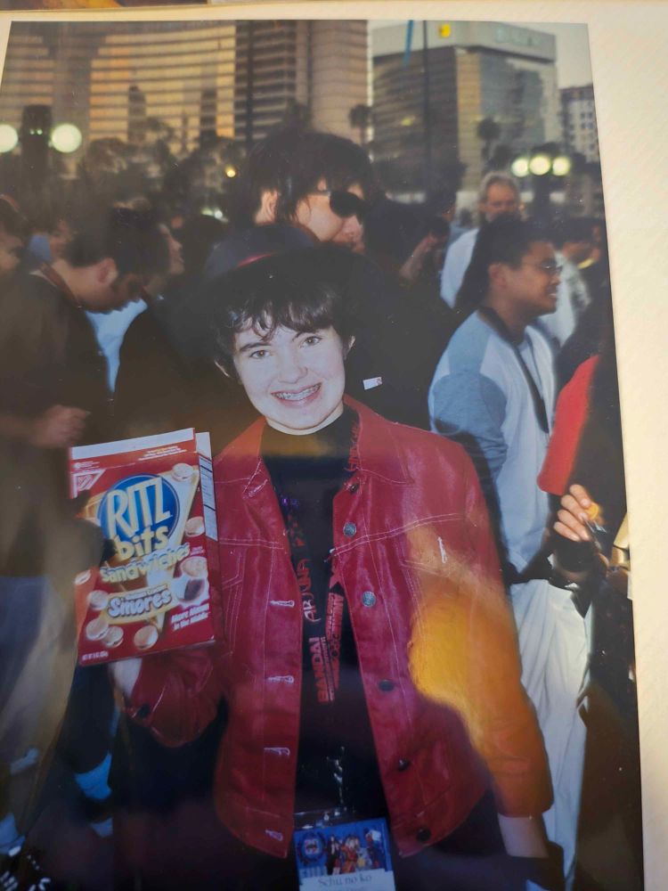 Internet idiot Schupuff in her late teens cosplaying Subaru Sumeragi from Tokyo Babylon happily holding a box of Ritz bits s'mores 