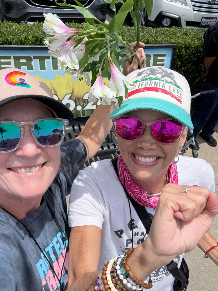 Two pro-democracy lesbians smiling and protesting #NoKings