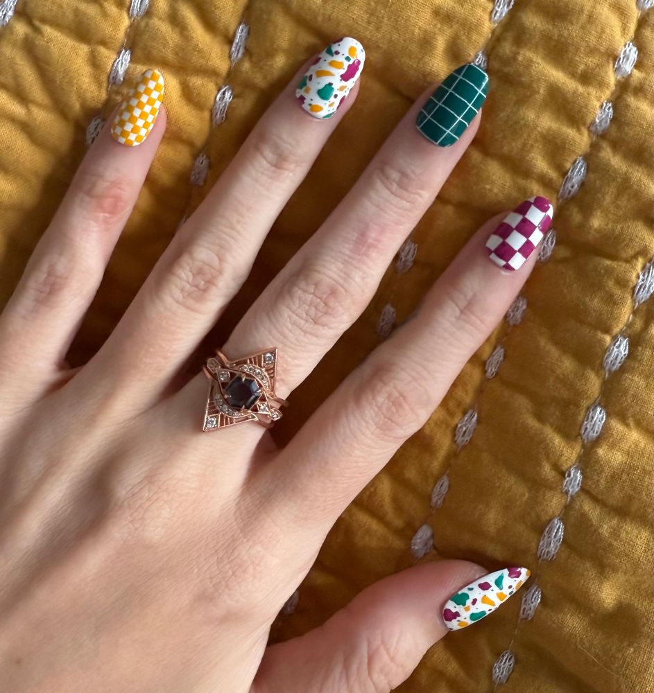 Pinky: yellow and white checkerboard
Ring finger and thumb: terrazzo pattern in purple, teal, and yellow on a white background 
Middle finger: dark teal with thin white gridded lines
Index finger: purple and white checkerboard 