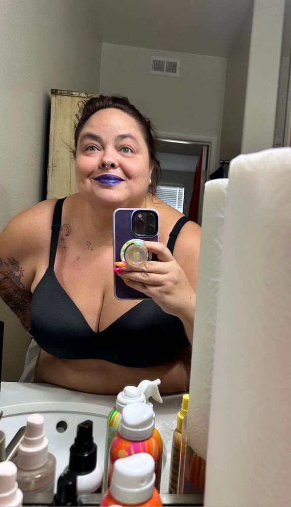 woman taking mirror selfie wearing purple lip stain 