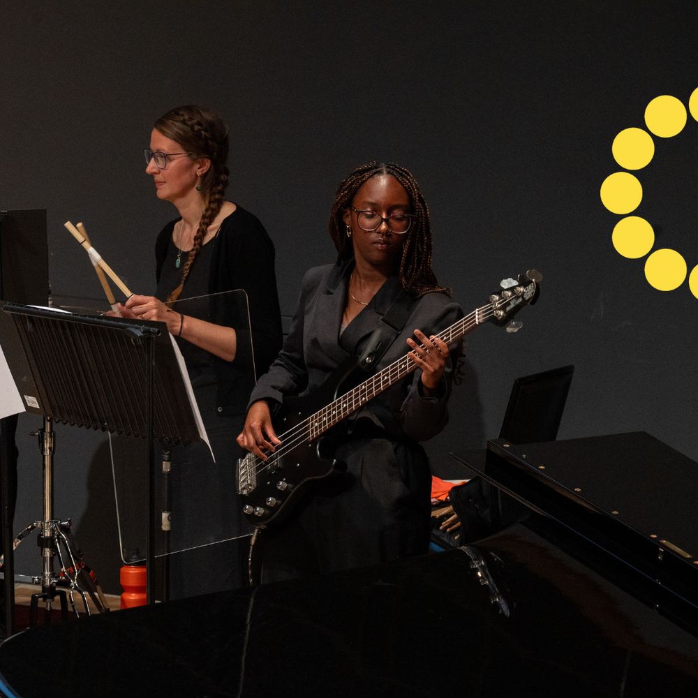 A young musician plays bass guitar on stage.