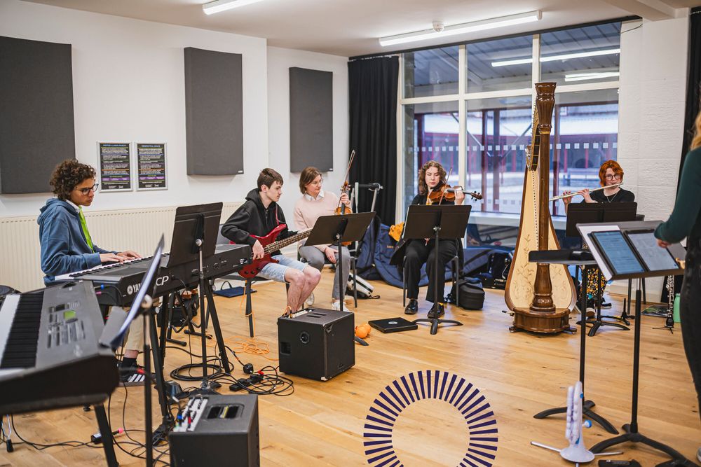A group of young disabled and non-disabled musicians rehearse together on acoustic and electronic instruments.