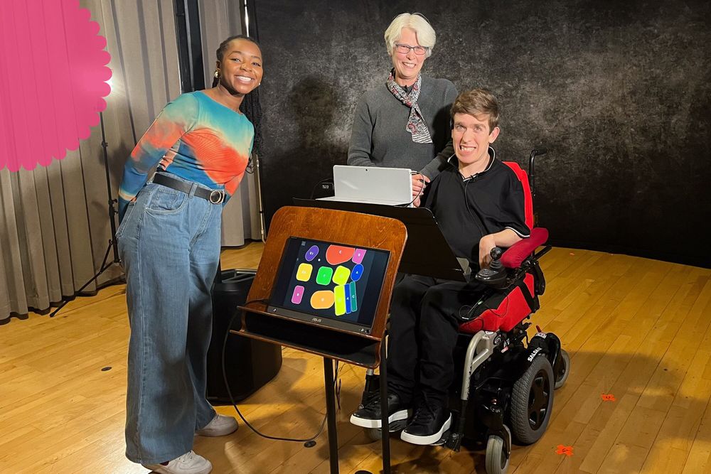 A female TV presenter, a woman and a young man pose for a photo. The young man is a wheelchair user and poses with the Clarion accessible instrument.