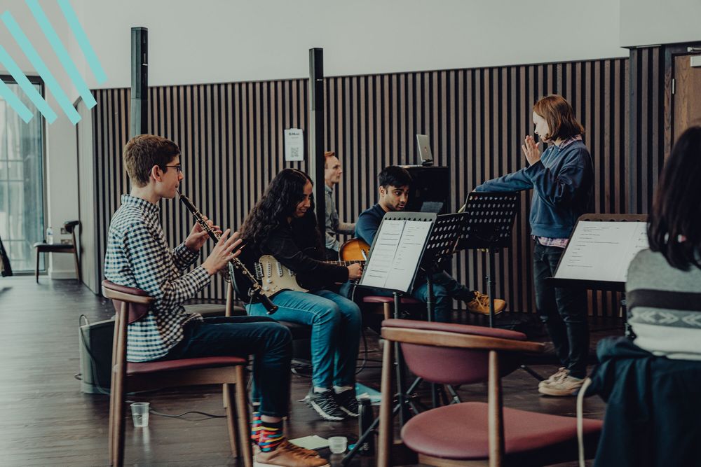 A group of young disabled and non-disabled musicians rehearse together on acoustic and electronic instruments.