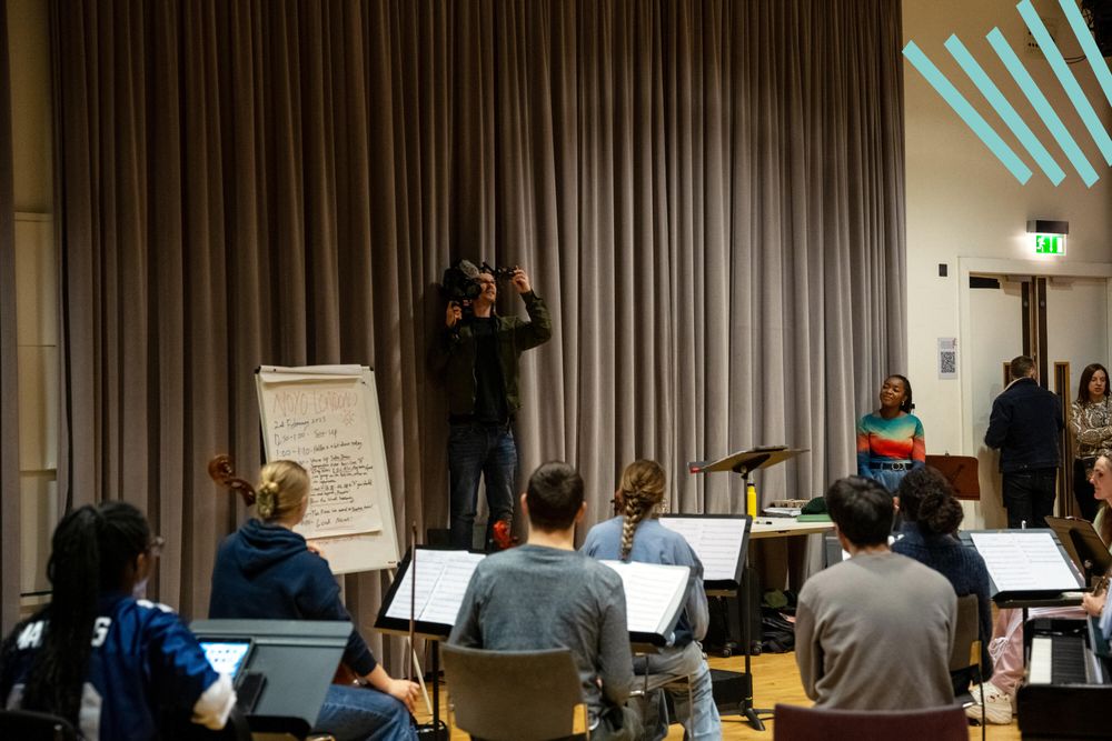 A camera operator films an orchestral rehearsal. The orchestra is made up of young disabled and non-disabled musicians.