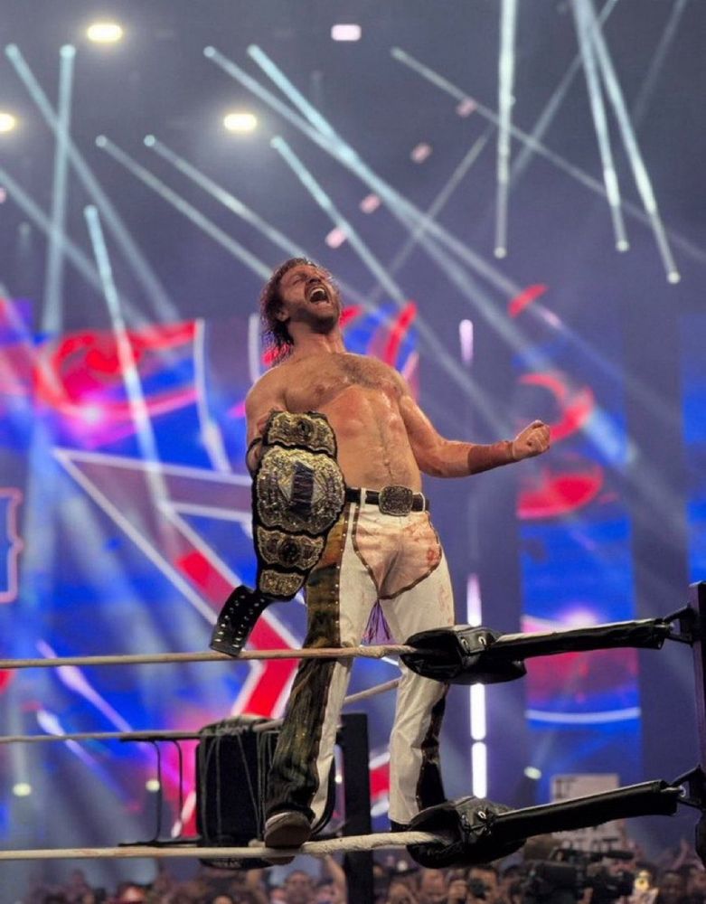 Hangman Adam Page triumphantly holding the AEW World Title.