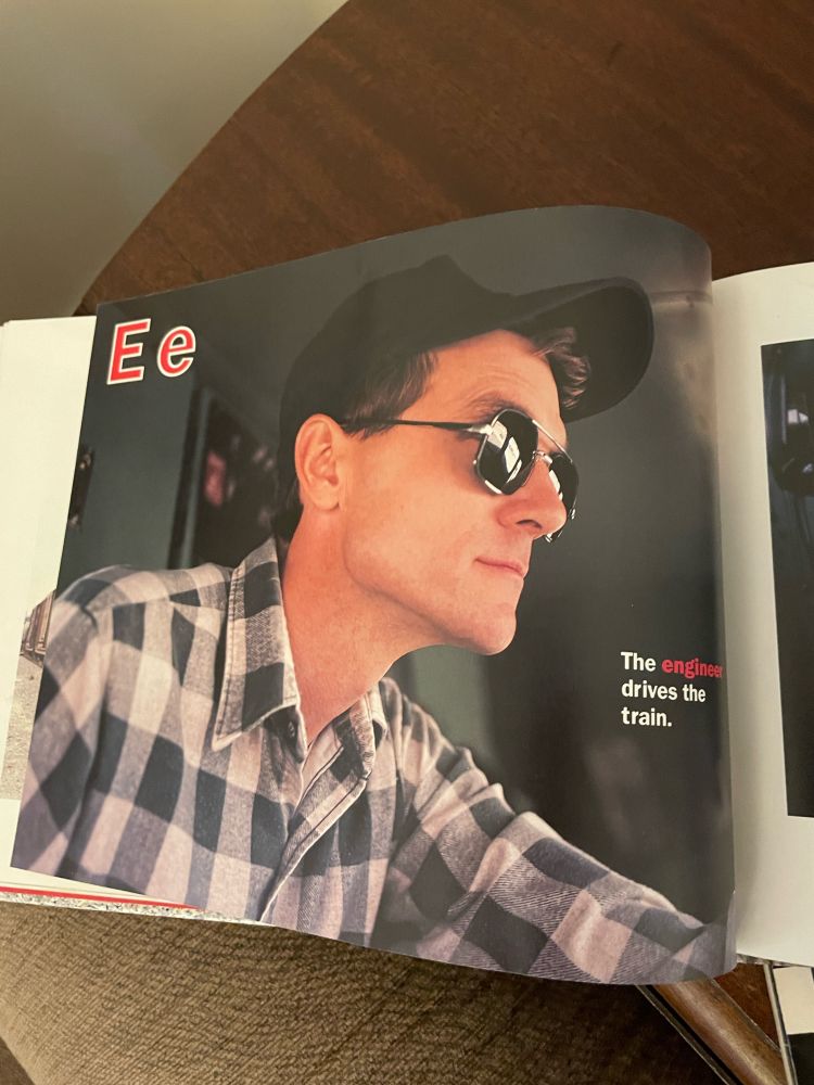 A picture from an alphabet book, letter e. The engineer drives the train. The engineer is peak 90s fashion.