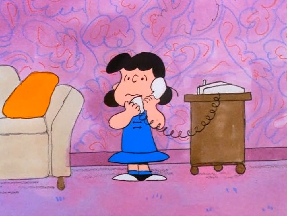 Lucy from the Peanuts gang on a landline phone with a concerned look on her face