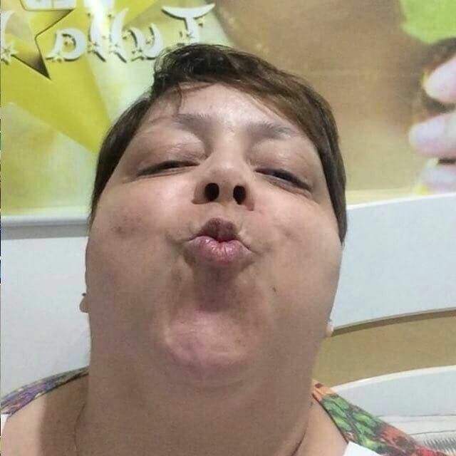 Uma mulher sentada numa cama branca e mandando beijo