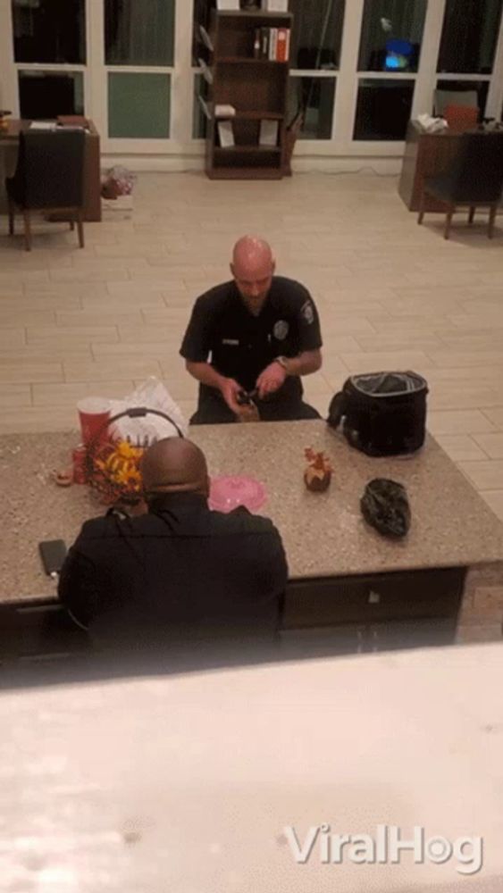 a police officer sits at a counter with another officer