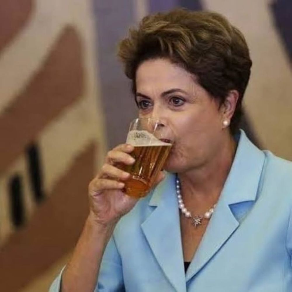 Dilma Rousseff de terninho azul e colar de pérolas tomando uma cerveja
