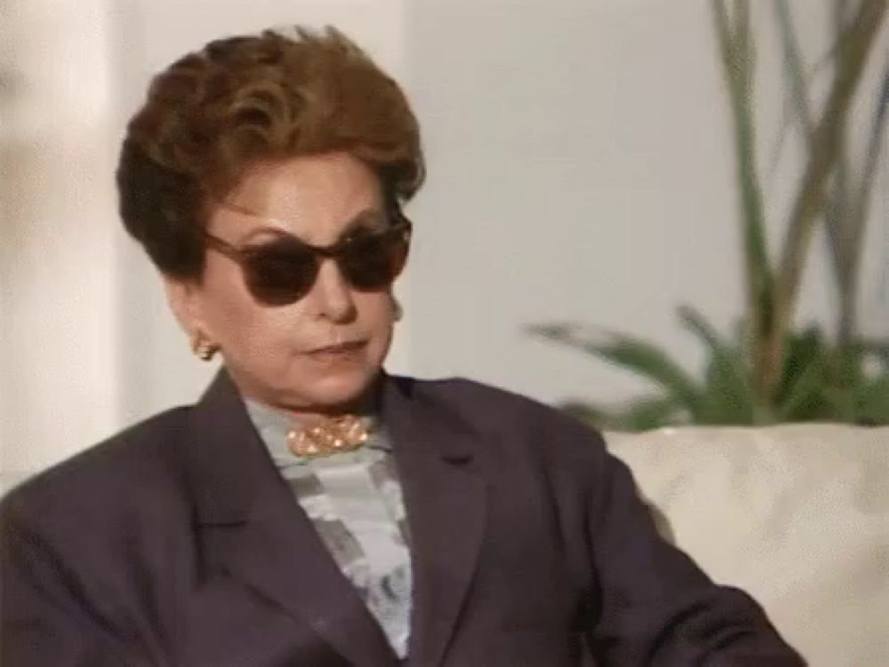 a woman wearing sunglasses is sitting on a couch .