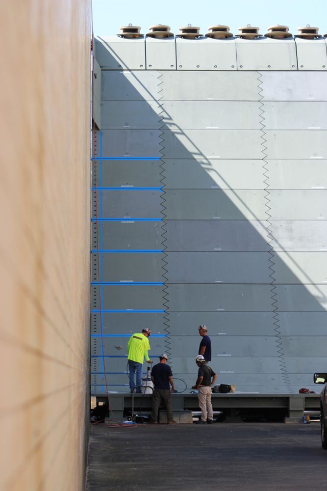 Technicians stand at the base of the new flame trench as they finish installing the panels.
