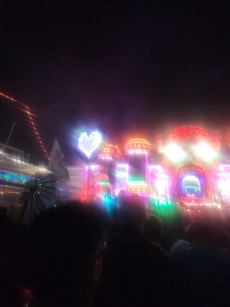 A shot of the main stage at Apocalypse. The lighting at the stage is vibrant and colorful. There is also a pixel heart totem in the crowd