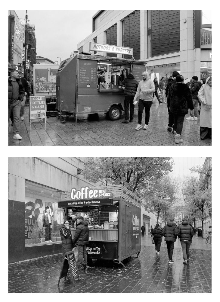Two Black and white photo made in a city center, showing two different catering trailers, one advertising hotdogs and burgers, the other selling coffee and crepes. Customers are waiting at each one.  